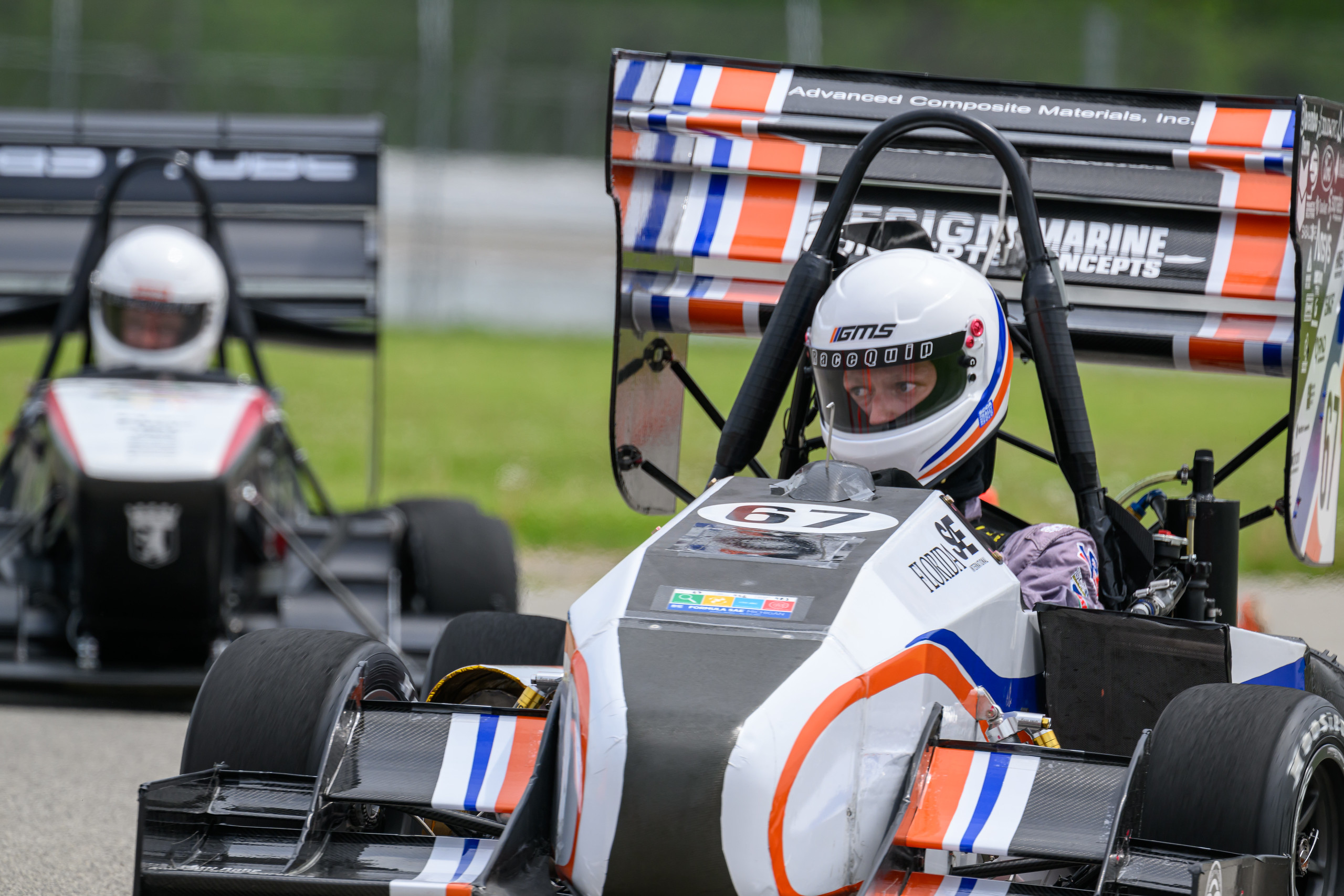 Image of the F23 car racing at competition, includes another formula team's car in the background